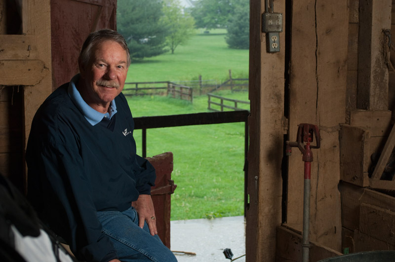man sitting in barn with door open to view of pasture