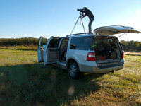 Edwina photographing in the field on top of a vehicle